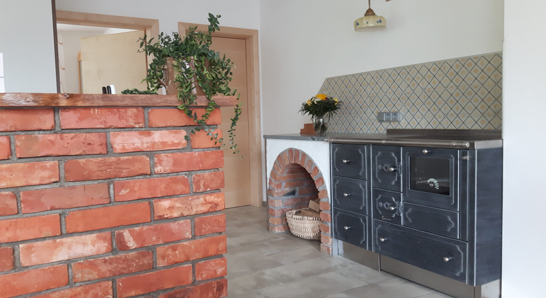 Der traditionelle Greithwald-Herd verleiht dieser Küche mit seinen klassischen Linien und der roten Ziegelumrandung eine gemütliche Eleganz © Greithwald